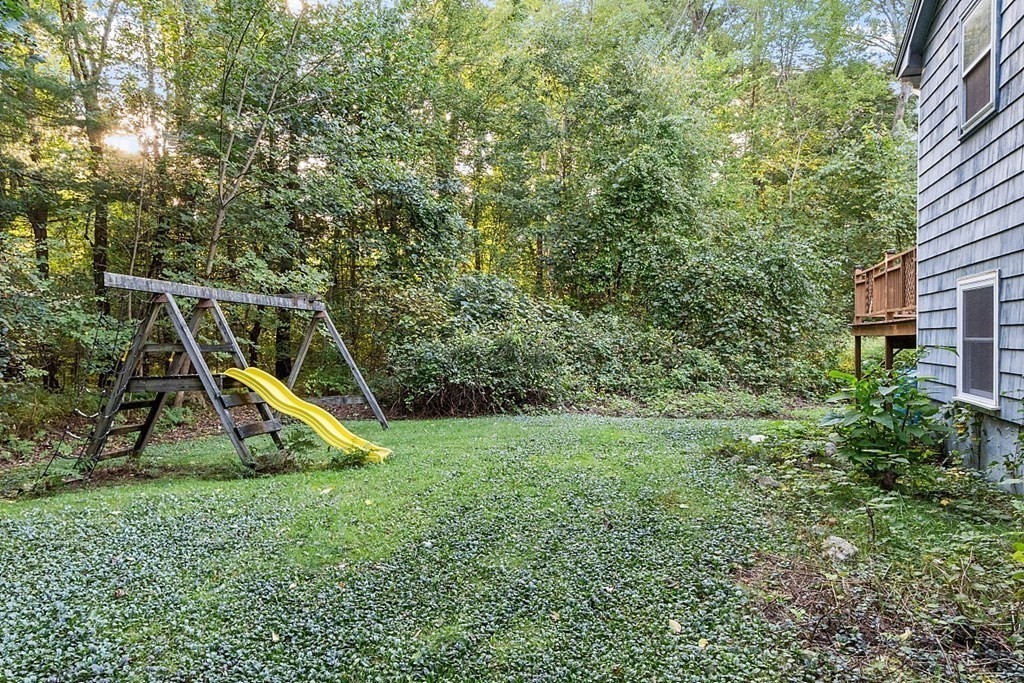 77 Hunt Road Chelmsford, MA 01824 - Photo 31 of 36 a view of a backyard with a slide trees and wooden fence