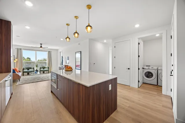 a large kitchen with stainless steel appliances kitchen island a large counter top a sink a refrigerator and a window