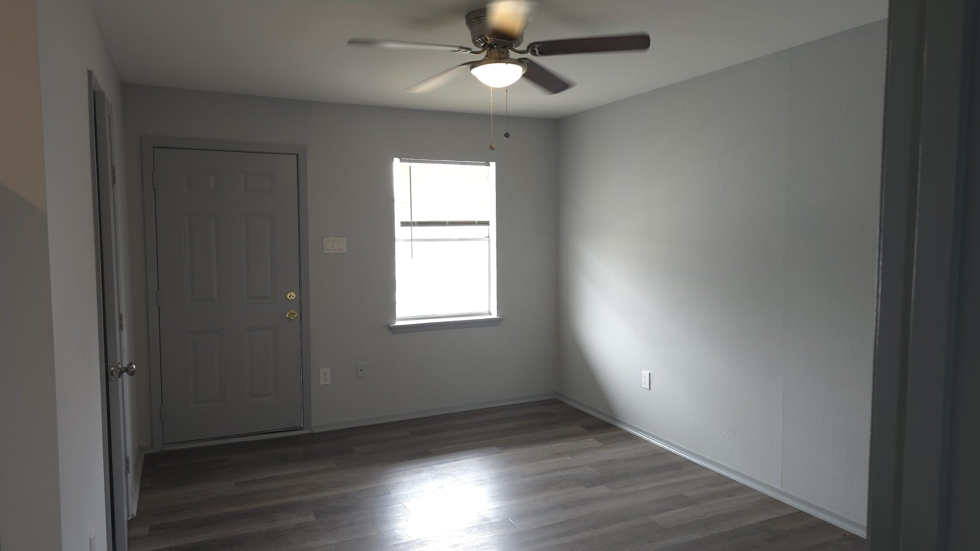 10209 Wiggins Street, Unit 10 Houston, TX 77029 - Photo 2 of 6 an empty room with wooden floor a ceiling fan and windows