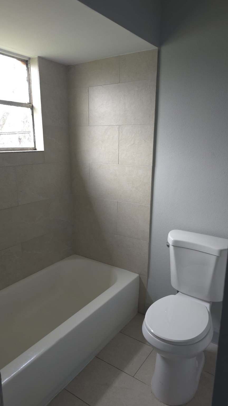 10209 Wiggins Street, Unit 10 Houston, TX 77029 - Photo 6 of 6 a white toilet sitting next to a bath tub