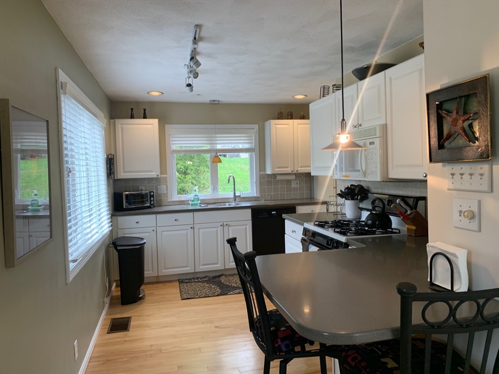 4 Potter Pond, Unit 4 Lexington, MA 02421 - Photo 11 of 15 a kitchen with kitchen island a dining table chairs stainless steel appliances and cabinets