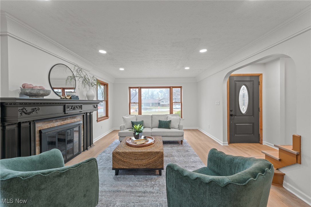 5266 Wilson Mills Road Cleveland, OH 44143 - Photo 7 of 50 Living room with crown molding, recessed lighting, a glass covered fireplace, arched walkways, and light wood-style flooring