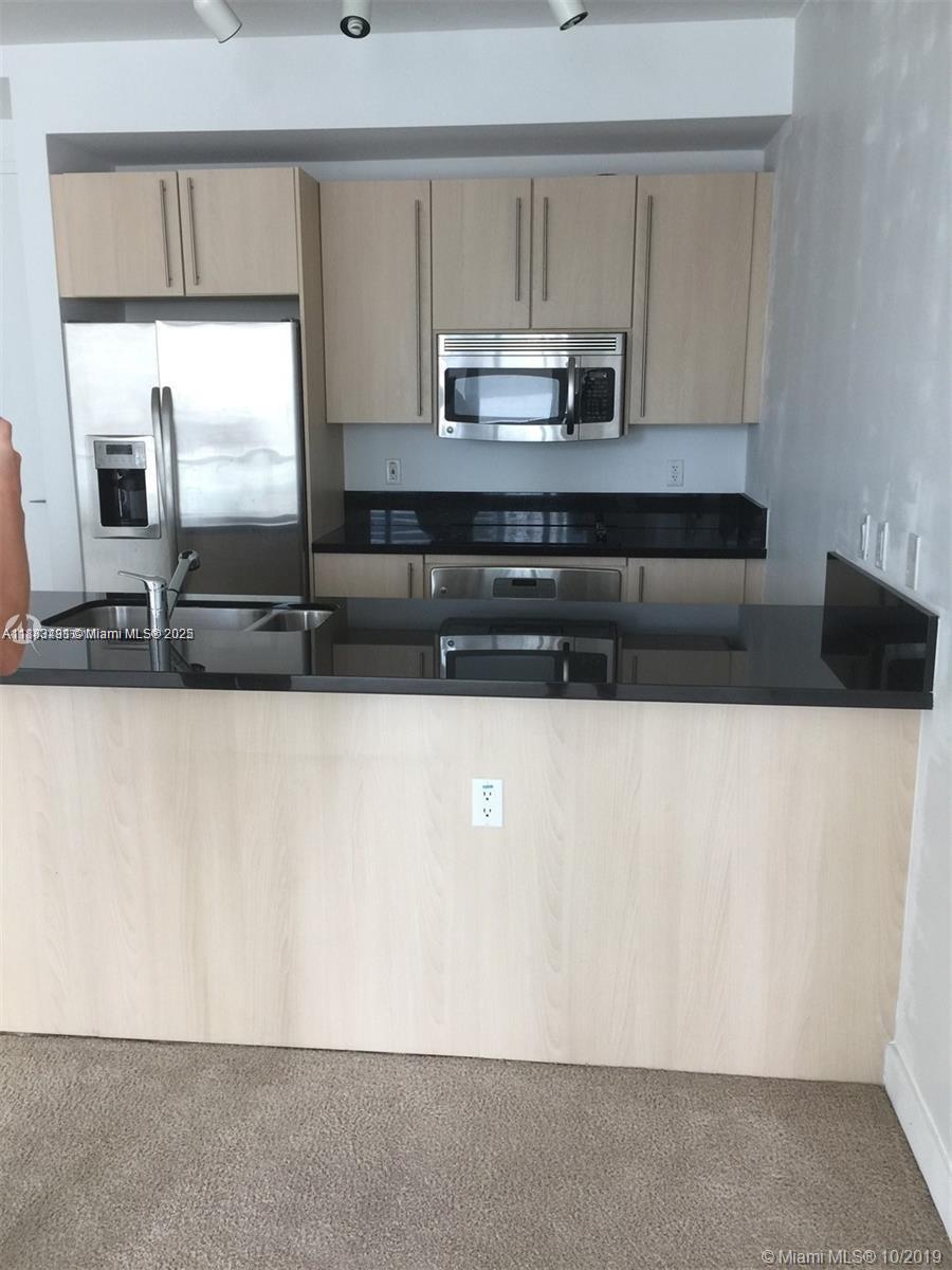 1111 Southwest 1st Avenue, Unit 1724N Miami, FL 33130 - Photo 13 of 17 a kitchen with stainless steel appliances a sink a stove a microwave a counter top and a cabinets