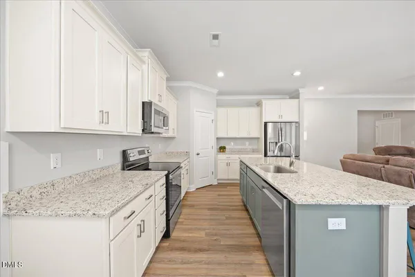 a kitchen with a refrigerator a stove a sink and white cabinets with wooden floor
