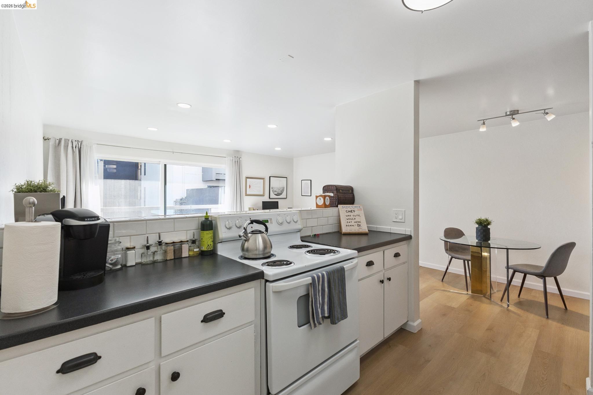5 Embarcadero, Unit 129 Oakland, CA 94607 - Photo 4 of 32 Kitchen with white electric stove, dark countertops, white cabinets, light wood-type flooring, and recessed lighting
