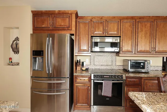 a kitchen with stainless steel appliances granite countertop a refrigerator stove and oven