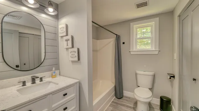 a bathroom with a granite countertop sink toilet a mirror and shower
