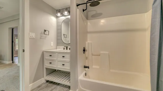 a bathroom with a bathtub shower sink vanity and a mirror
