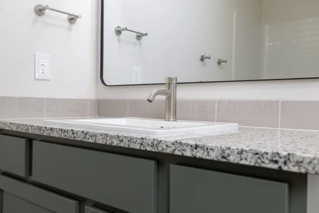 a bathroom with a granite countertop sink and a mirror