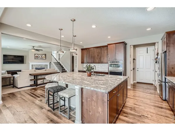 a kitchen with stainless steel appliances kitchen island granite countertop a table chairs refrigerator and microwave