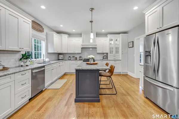 a kitchen with stainless steel appliances granite countertop a refrigerator a stove a sink dishwasher and a refrigerator with wooden floor