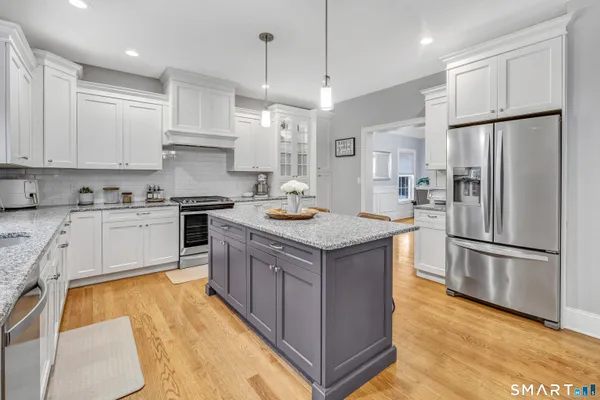a kitchen with stainless steel appliances granite countertop a sink a stove a refrigerator and island with wooden floor