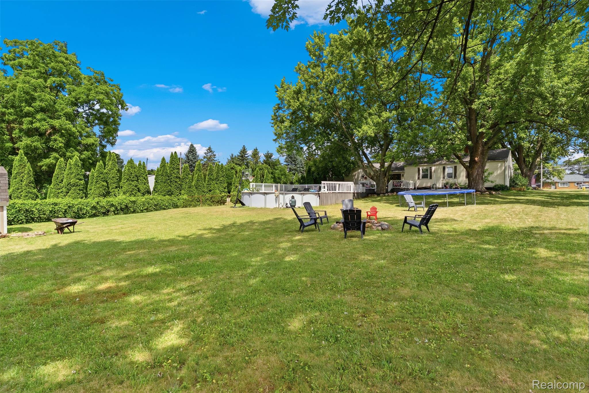 8403 Miller Road Swartz Creek, MI 48473 - Photo 28 of 37 Expansive backyard featuring a lush lawn, mature trees, and a visible above-ground pool