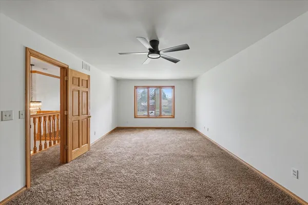 an empty room with closet and a chandelier fan