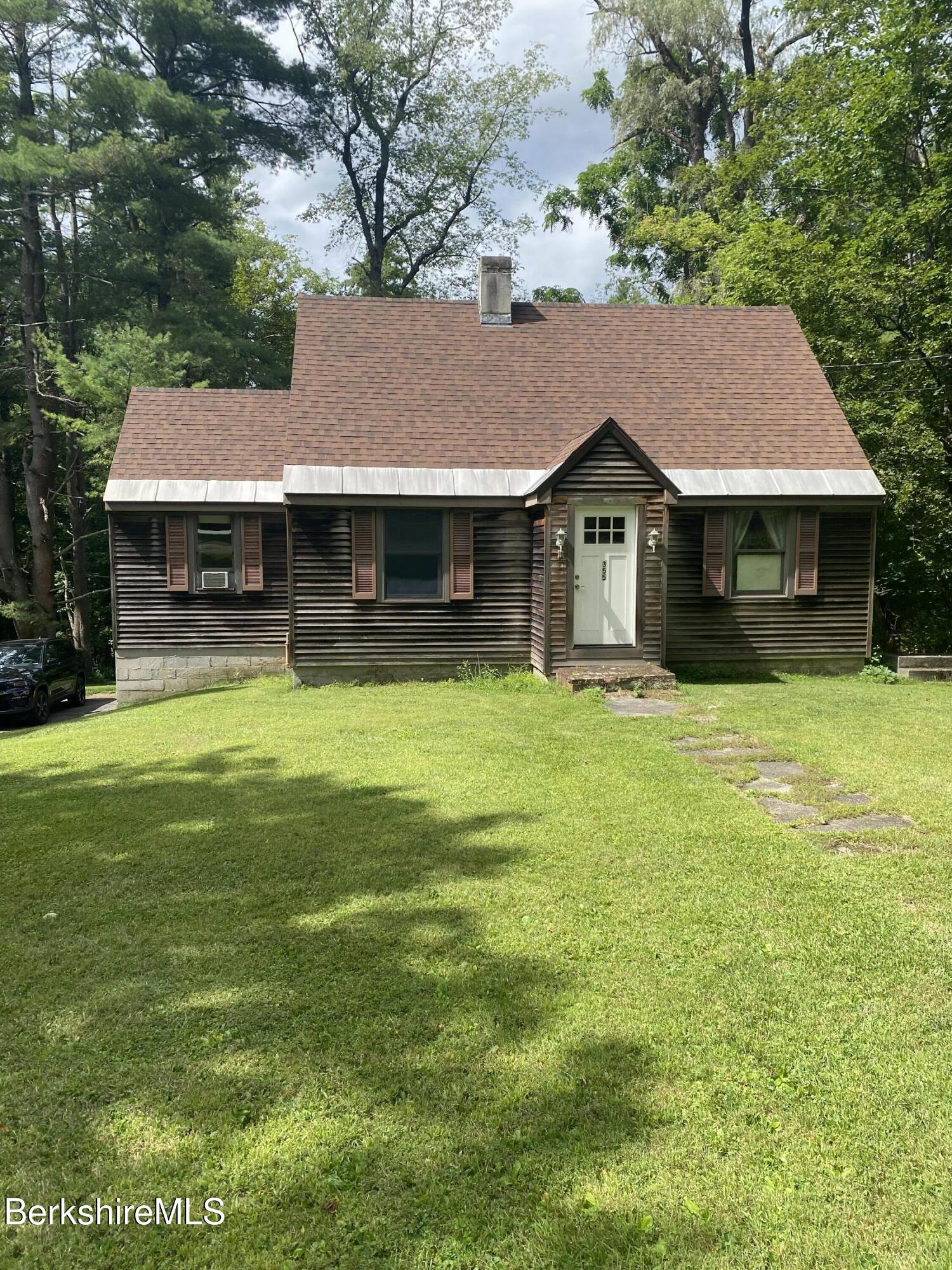 a front view of house with yard and trees in the background