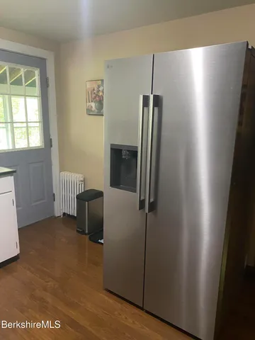 a view of a refrigerator in kitchen and an empty room