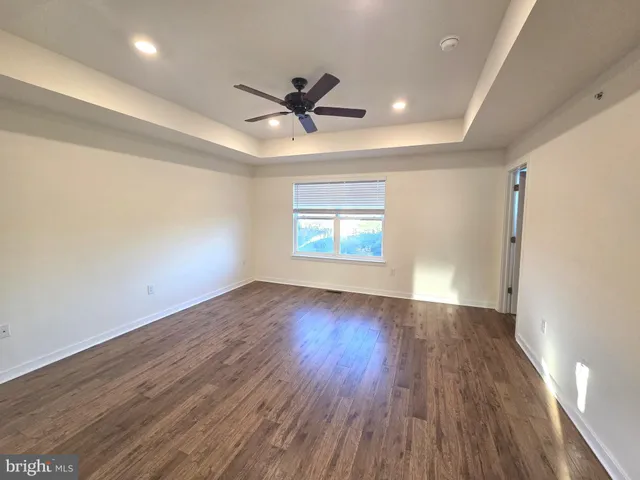an empty room with wooden floor a ceiling fan and windows