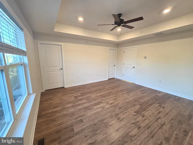a view of empty room with wooden floor and fan