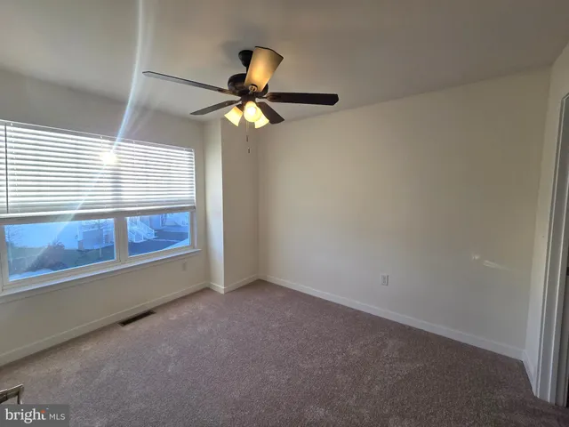 an empty room with a window and a ceiling fan