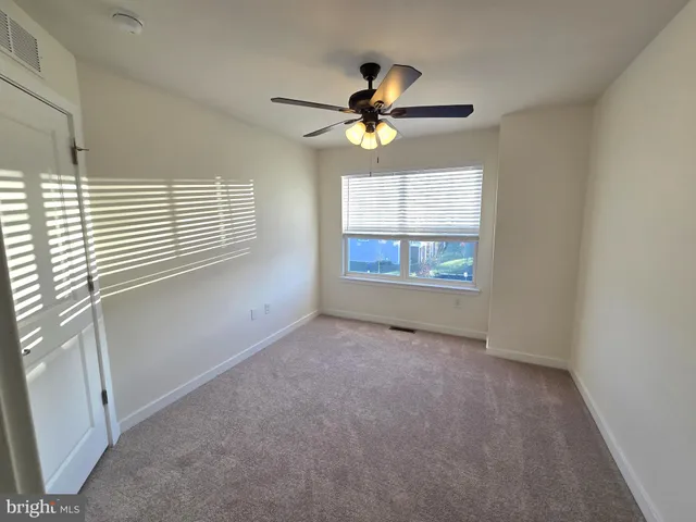 an empty room with windows and fan