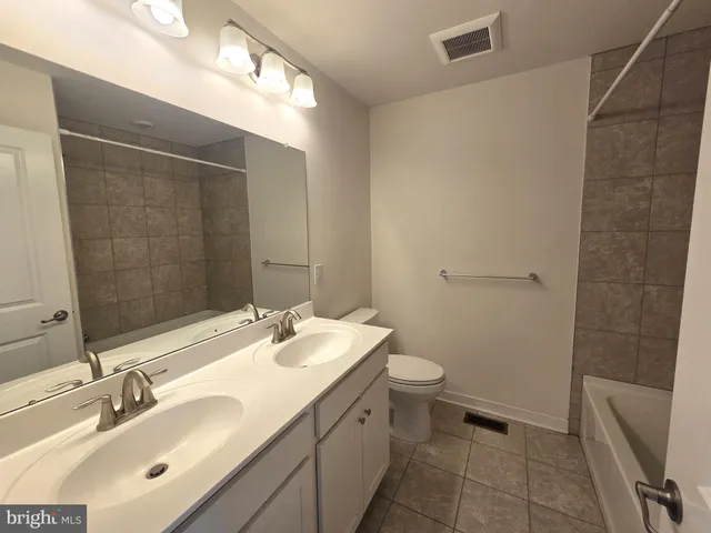 a bathroom with a double vanity sink toilet and a mirror