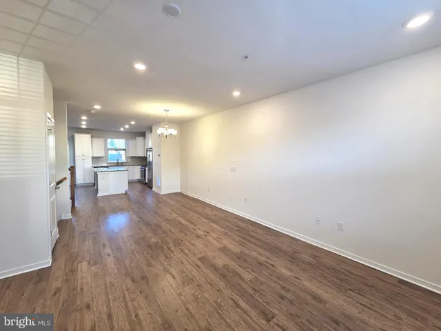 a view of a big room with wooden floor a kitchen view and a window