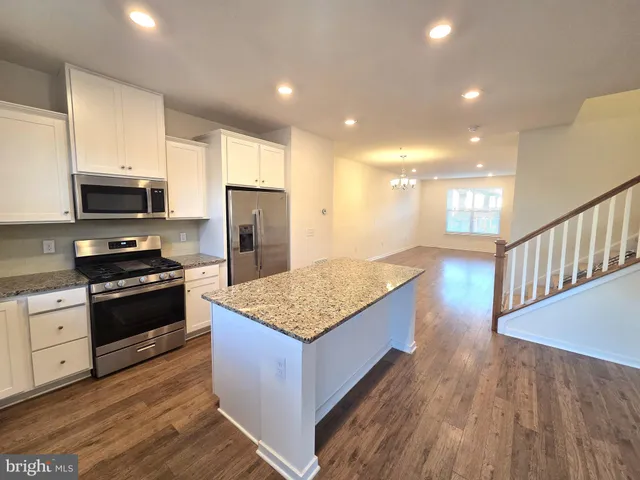 a kitchen with stainless steel appliances kitchen island granite countertop a stove a refrigerator and a microwave