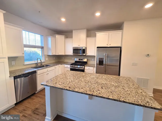 a kitchen with granite countertop stainless steel appliances a sink stove and refrigerator