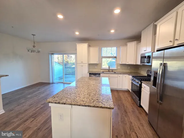 a kitchen with granite countertop kitchen island wooden floors granite counter tops and a window