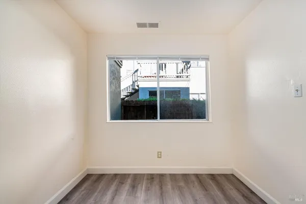 a view of an empty room with a window and wooden floor