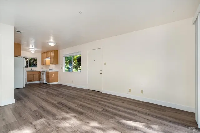 a view of a hallway with wooden floors and cabinet