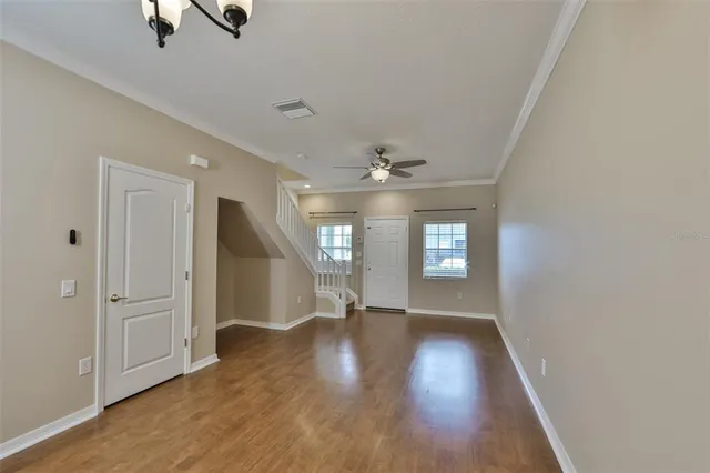 an empty room with wooden floor and windows