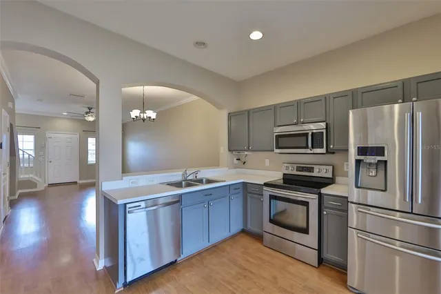 a kitchen with stainless steel appliances granite countertop a stove a sink dishwasher a refrigerator and a stove with wooden floor