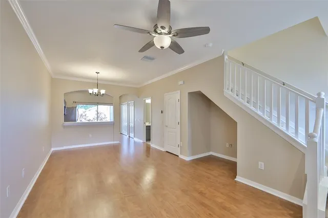 a view of an empty room with window and ceiling fan