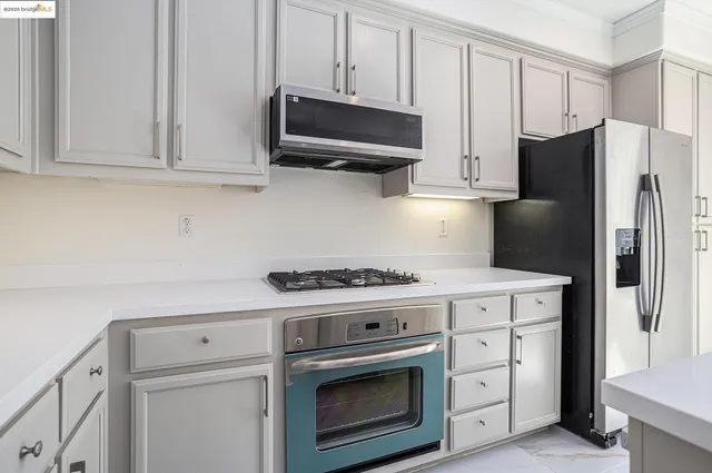 a kitchen with stainless steel appliances white cabinets and a stove a refrigerator with white cabinets