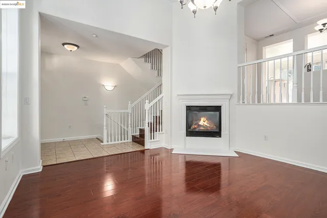 an empty room with wooden floor fireplace and windows