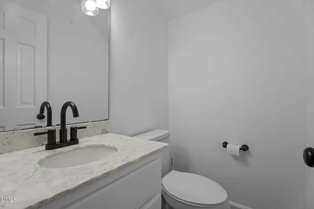 a bathroom with a granite countertop toilet and a sink