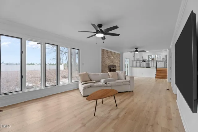 a living room with furniture and a large window with kitchen view