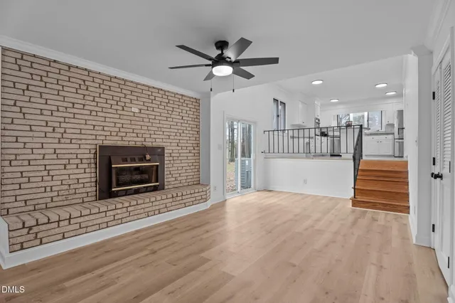 a view of a livingroom with a ceiling fan fireplace and wooden floor
