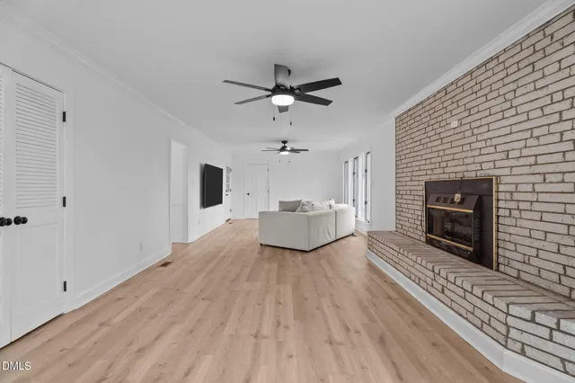 a view of a livingroom with a fireplace a ceiling fan a fireplace and windows