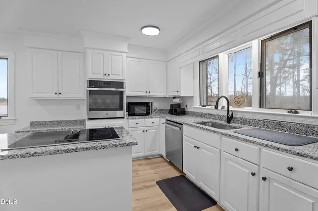 a kitchen with sink a stove and white cabinets