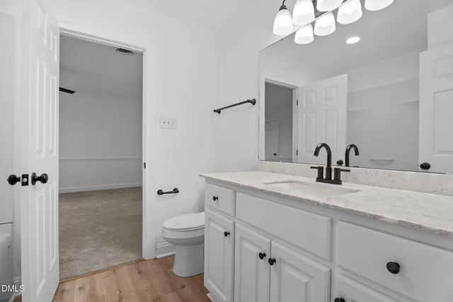 a spacious bathroom with a granite countertop sink a toilet and a mirror