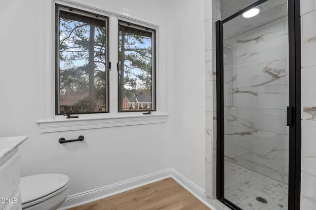 a bathroom with a window a toilet and a shower