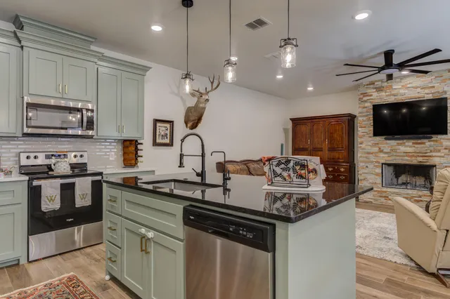 a kitchen with granite countertop a stove a sink and a microwave