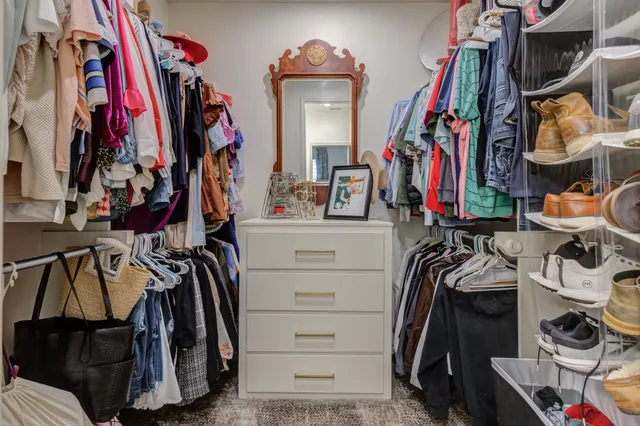 a view of walk in closet with clothes and shoes