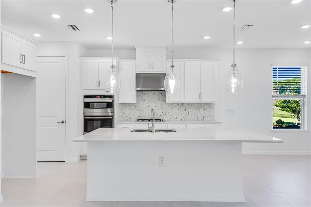 581 Moon Shell Circle New Smyrna Beach, FL 32168 - Photo 3 of 40 a large kitchen with kitchen island white cabinets and stainless steel appliances