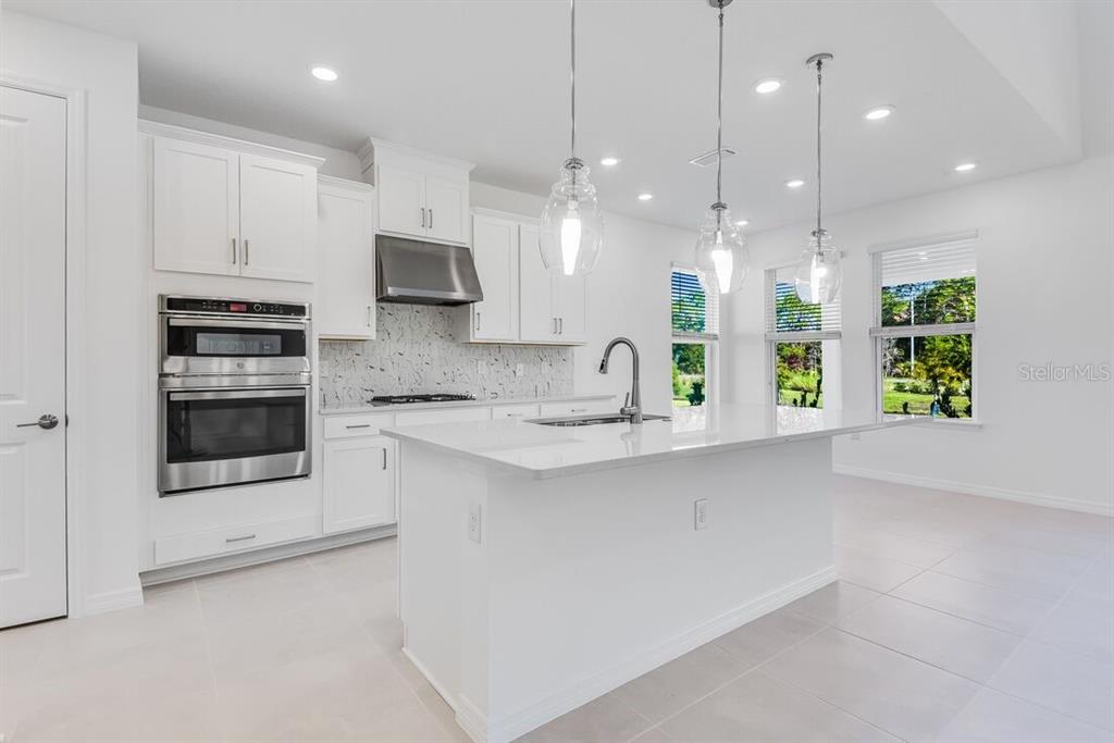 581 Moon Shell Circle New Smyrna Beach, FL 32168 - Photo 6 of 40 a kitchen with stainless steel appliances kitchen island granite countertop a stove a sink and a microwave