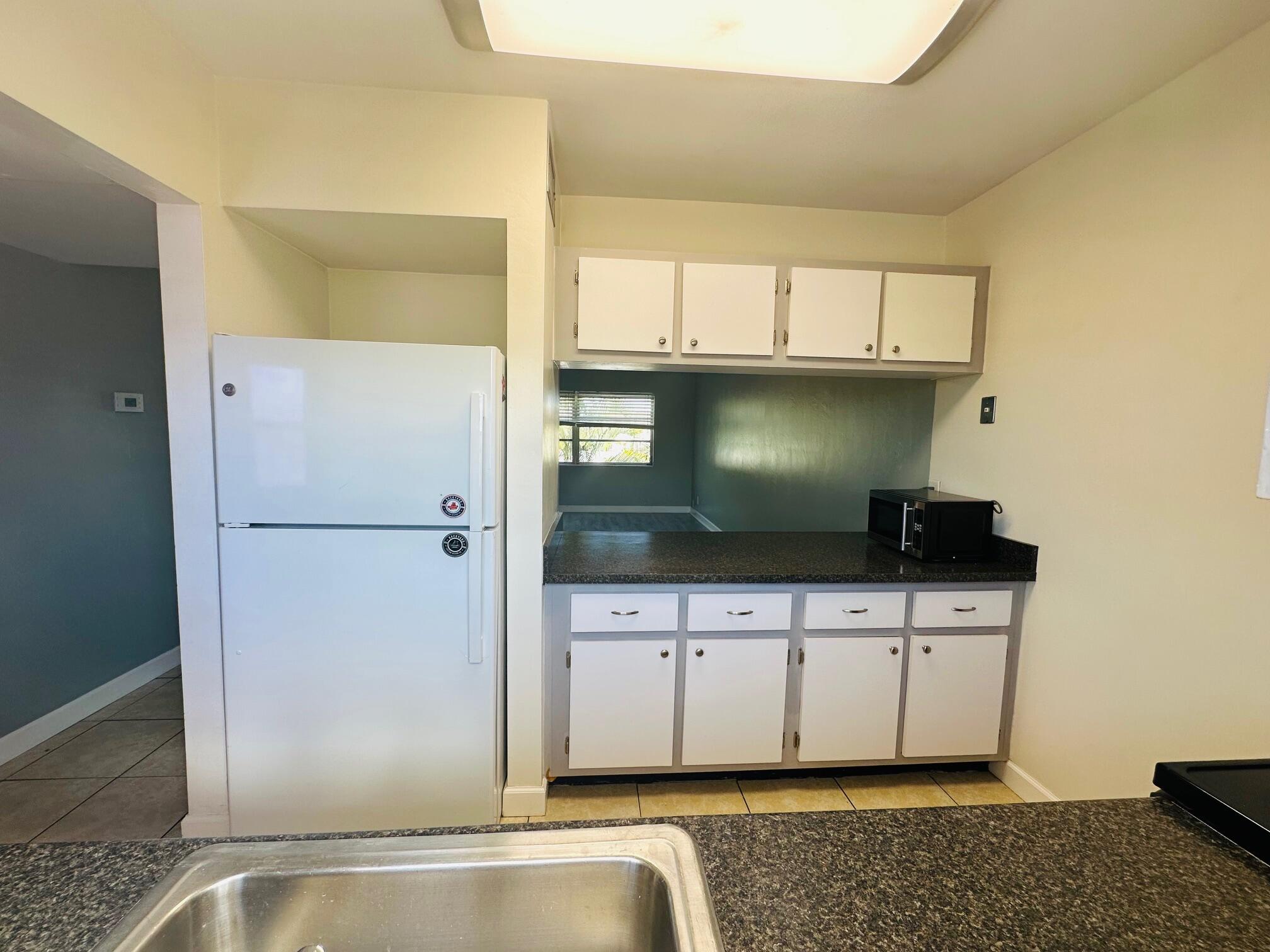 761 Hummingbird Way, Unit 205 North Palm Beach, FL 33408 - Photo 8 of 16 a kitchen with stainless steel appliances granite countertop a refrigerator and a sink