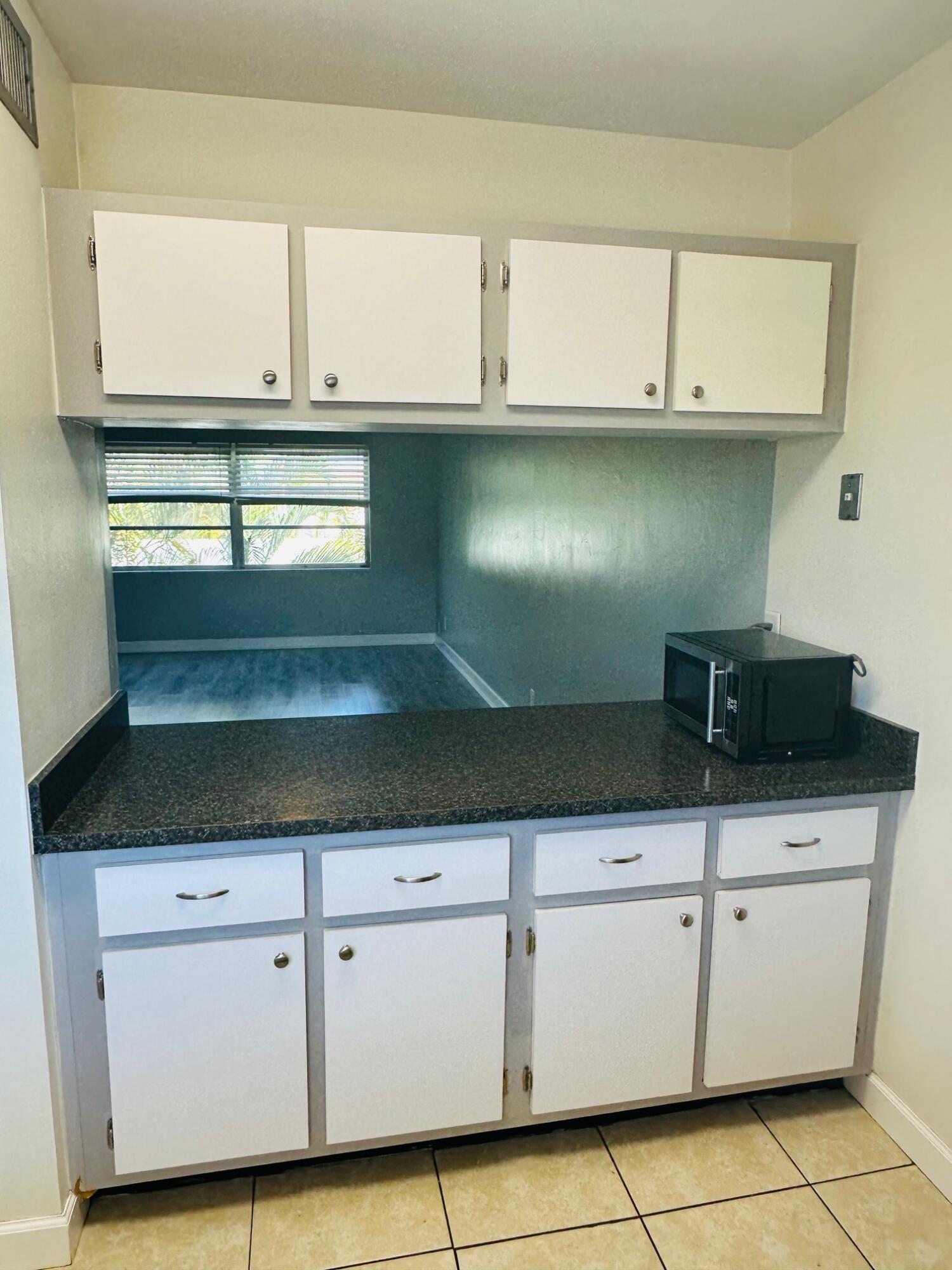 761 Hummingbird Way, Unit 205 North Palm Beach, FL 33408 - Photo 9 of 16 a kitchen with white cabinets and a stove