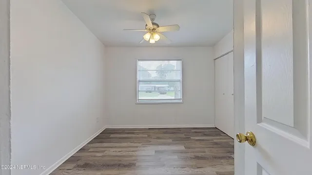 a view of an empty room and window and chandelier fan